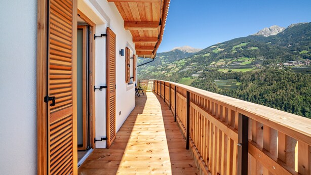 A wooden balcony with a view of a mountainous landscape. - Apartment 'Huetterhof Langes' with Mountain View, Private Terrace and Wi-Fi (Caines)