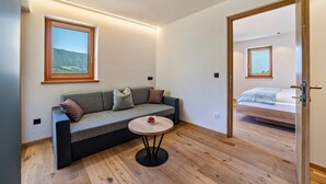 A modern room with a sofa, a small round table, and a bed. - Apartment 'Huetterhof Langes' with Mountain View, Private Terrace and Wi-Fi (Caines)