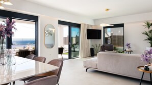 Ein modernes Wohnzimmer mit einer Couch, einem Esstisch mit Stühlen und einem an der Wand montierten Fernseher.