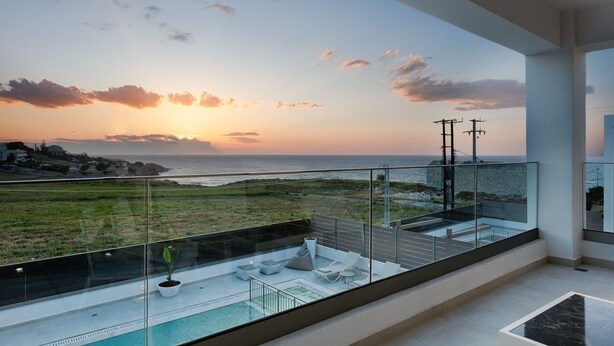 Ein moderner Balkon mit Glasgeländer, der einen Pool und einen Sonnenuntergang zeigt.