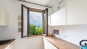 A kitchen with a window, white cabinets, a countertop, and a kettle. - Apartment 'Villa Verde' with Lake View, Shared Pool and Air Conditioning (Torri del Benaco)