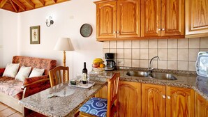 Una cocina con armarios de madera, encimera de granito, un lavabo, una mesa de comedor y un sofá.