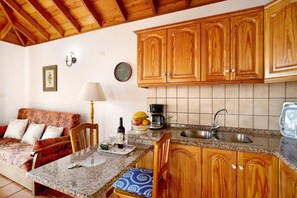 Una cocina con armarios de madera, encimera de granito, un lavabo, una mesa de comedor y un sofá.