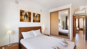 Una habitació d'hotel amb llit, taulells laterals, mirall i obra d'art a la paret.