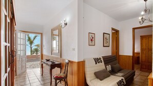 A living room with a sofa, a dining table, and chairs, a wooden cabinet, and a large mirror. - Holiday Home 'Casa Ariadna' with Sea Views, Private Garden, and Wi-Fi (Tijarafe)