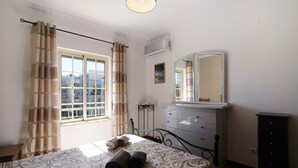 A bedroom with a bed, a dresser, a mirror, and a window with curtains. - Apartment 'Golden Rana' with Shared Pool, Wi-Fi and Air Conditioning (Albufeira)