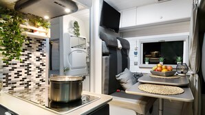 A compact kitchenette with a stove, a sink, and a small countertop. - Adventure Campingvan with Sea Views and Air Conditioning (Lanzarote)