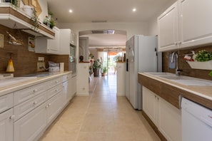 A modern kitchen with white cabinets, a dishwasher, and a countertop with a sink.