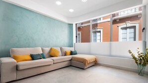 A modern living room with a beige sectional sofa, a small ottoman, and a potted plant. - Vacation Apartment 'Trébol' with Wi-Fi (Santa Cruz de Tenerife)