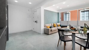 A modern kitchen with white cabinets, a dining area with a round table and chairs, and a sofa with colorful cushions. - Vacation Apartment 'Trébol' with Wi-Fi (Santa Cruz de Tenerife)