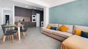 A modern living room with a sofa, dining table, chairs, and a kitchen area in the background. - Vacation Apartment 'Trébol' with Wi-Fi (Santa Cruz de Tenerife)