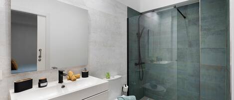 A modern bathroom with a glass-enclosed shower, a white sink, and a toilet.