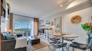 A modern living room with a sofa, coffee table, and a dining area with a round table and chairs.