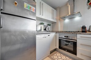 Une cuisine moderne dotée d’appareils électroménagers en acier inoxydable, de meubles blancs et d’un sol à motifs.