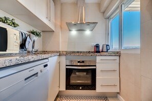 A modern kitchen with a built-in oven, a dishwasher, and a window with a view.
