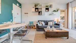 A modern living room with a grey sofa, a coffee table, and a dining area with a white table and chairs.
