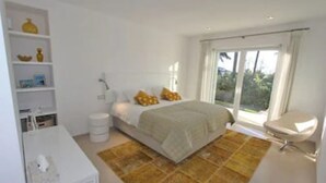 A bedroom with a bed, bedside table, lamp, and a window with curtains. - Villa 'Nagueles' with Sea View, Wi-Fi and Air Conditioning (Marbella)