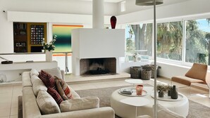 A modern living room with a fireplace, a sofa, a coffee table, and a large window. - Villa 'Nagueles' with Sea View, Wi-Fi and Air Conditioning (Marbella)