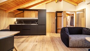 Eine moderne Küche mit Holzbalken, einer schwarzen Arbeitsplatte und einer Couch im Wohnbereich.