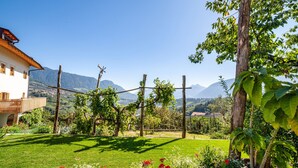 Ein Haus mit Balkon, ein Garten voller Blumen und Berge im Hintergrund.