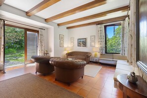 Un salon comprenant un canapé, une banquette rembourrée, une table basse en bois et une grande fenêtre avec des rideaux.