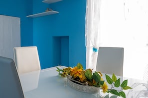 Una habitaci ón con pared azul, muebles blancos y una planta decorativa sobre una mesa.