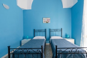 Una habitación con dos camas, un cuadro pequeño y una ventana con cortinas.