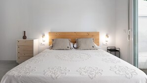 Ein Schlafzimmer mit einem Bett, zwei Nachttischlampen, einem Nachttisch und einer Kommode.
