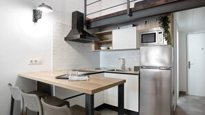 Eine moderne Küche mit einem Holztisch, zwei Stühlen, einem Edelstahlkühlschrank und einer Mikrowelle.