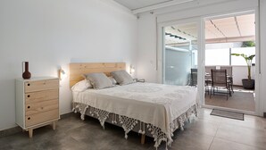 Ein Schlafzimmer mit Bett, Nachttisch und Blick auf die Terrassenanlage.