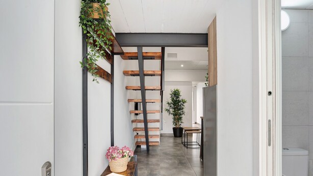 Ein Flur mit einer hölzernen Sitzbank, einem Blumentopf und einer Treppe.