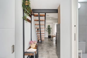 Un couloir avec un banc en bois, une plante en pot et un escalier.