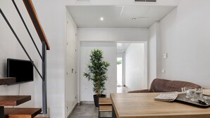 Ein modernes Interieur mit Treppe, Essbereich, Topfpflanze und Fernseher.