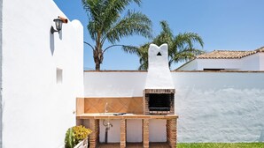 A patio with a brick grill, a sink, and a planter with yellow flowers. - Holiday Home 'Villa Cala Salada' with Private Pool, Wi-Fi and Air Conditioning (Conil de la Frontera)