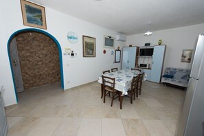 A compact kitchen with a dining area, a stone wall, and a blue archway. - Apartment "Mariposa" with Mountain View, Shared Terrace & Wi-Fi (Orosei)
