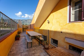 A patio with a table and benches, potted plants, and a view of mountains. - Apartment "Mariposa" with Mountain View, Shared Terrace & Wi-Fi (Orosei)