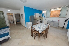 A compact living space with a dining area, kitchenette, and a bed. - Apartment "Mariposa" with Mountain View, Shared Terrace & Wi-Fi (Orosei)
