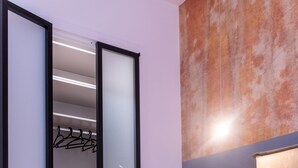 A hotel room with a bed, a wardrobe with a mirror, and a wall with a textured pattern.