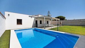 Une piscine avec une maison blanche en arrière-plan.