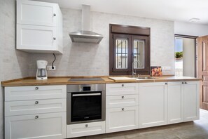 Una cocina moderna con armarios blancos, un horno Bosch, una cafetera y una ventana con vistas.