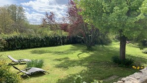 Un jardin bien entretenu, agrémenté d’un mur en pierre, d’une pelouse et d’un arbre qui offre de l’ombre.