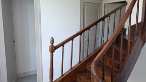 Un escalier en bois avec une rampe, un revêtement de sol en moquette et des murs blancs.