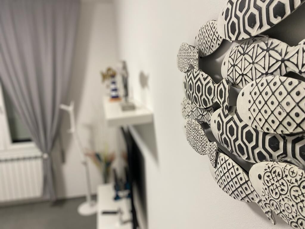 A room with a white wall, a window with a curtain, and a shelf with various items.