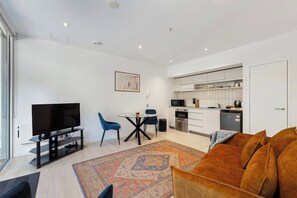 A modern living room with a flat-screen TV, a coffee table, and a sofa.