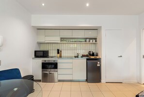 A compact kitchen with white cabinets, a microwave, a stove, and a refrigerator.