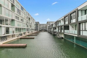 A modern building with a water canal in the middle, featuring multiple levels with glass railings and a clear sky above.