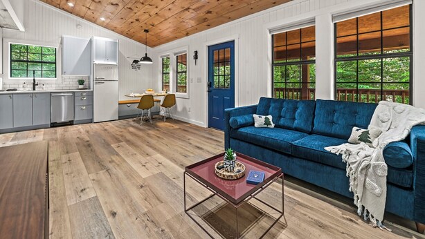A modern kitchen with white cabinets, a blue door, and large windows.
