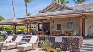 A covered outdoor seating area with lounge chairs, a stone wall, and a sign indicating 'Duties'.