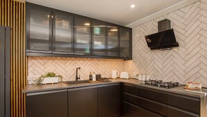 Une cuisine moderne avec des meubles de couleur sombre, un dosseret orné d’un motif en chevrons, une cuisinière encastrée et un four à micro-ondes.