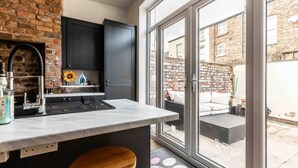 Une cuisine moderne équipée d’un four encastré, d’un évier et d’un coin bar. Une grande fenêtre offre une vue sur l’extérieur.